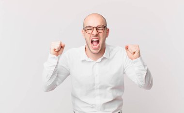 Kel adam öfkeli bir ifadeyle ya da yumruklarıyla başarıyı kutlarken agresif bir şekilde bağırıyor.