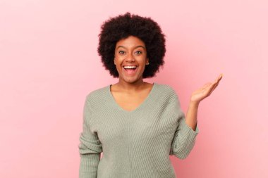 Afro siyah kadın kendini mutlu, şaşırmış ve neşeli hissediyor, olumlu bir tavırla gülümsüyor, bir çözüm ya da fikri fark ediyor.