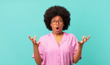 Afro siyahi kadın ağzı açık ve şaşırmış, şok olmuş ve hayrete düşmüş inanılmaz bir sürprizle