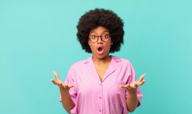 Afro siyah kadın aşırı derecede şok olmuş ve şaşırmış, endişeli ve paniklemiş hissediyor, stresli ve dehşete kapılmış bir bakışla