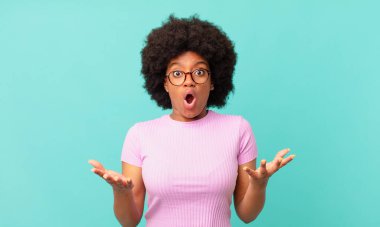 Afro siyahi kadın ağzı açık ve şaşırmış, şok olmuş ve hayrete düşmüş inanılmaz bir sürprizle