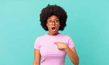 Afro siyah kadın şok olmuş ve şaşırmış görünüyor ağzı açık, kendini işaret ediyor.