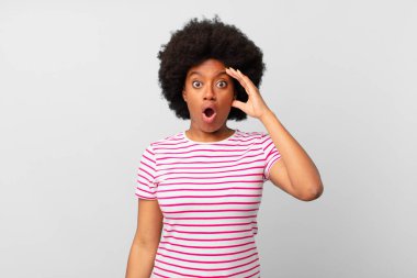 Afro siyah kadın mutlu, şaşkın ve şaşırmış görünüyor, gülümsüyor ve inanılmaz ve inanılmaz iyi haberleri fark ediyor.