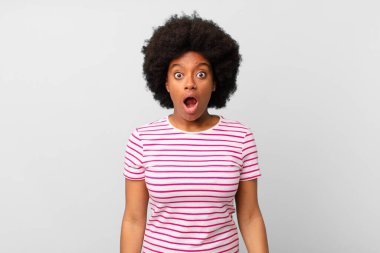 Afro siyah kadın şok olmuş ya da şaşırmış görünüyor, ağzı açık bir şekilde 