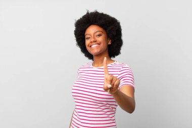 Afro siyah kadın gururla gülümsüyor ve gururla bir numaralı pozu veriyor, kendini lider gibi hissediyor.