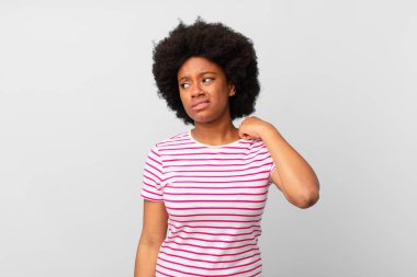 Afro siyahi kadın stresli, endişeli, yorgun ve hayal kırıklığına uğramış, gömleğini çekiştirmiş, sorunlu görünüyor.