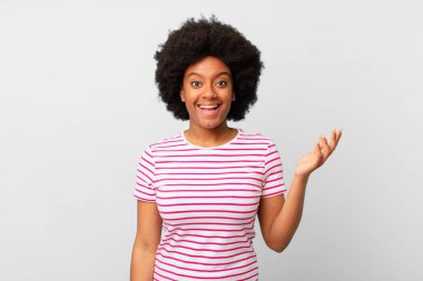 Afro siyah kadın kendini mutlu, şaşırmış ve neşeli hissediyor, olumlu bir tavırla gülümsüyor, bir çözüm ya da fikri fark ediyor.