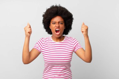 Afro siyah kadın öfkeli bir ifadeyle ya da yumruklarıyla başarıyı kutlarken agresif bir şekilde bağırıyor.