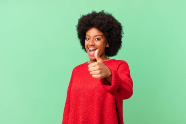 Afro siyah kadın gururlu, kaygısız, kendinden emin ve mutlu, olumlu gülümsüyor.