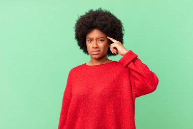 Afro siyah kadın şaşkın ve şaşkın hissediyor, deli, deli ya da aklını kaçırmış olduğunu gösteriyor.