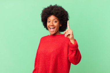 Afro siyah kadın bir fikri fark ettikten sonra mutlu ve heyecanlı bir dahi gibi hissediyor, neşeli bir şekilde parmağını kaldırıyor, eureka!