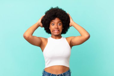 Afro siyah kadın kendini stresli, endişeli, endişeli ya da korkmuş hissediyordu. Elleri başının üstünde, hatayla panikliyordu.