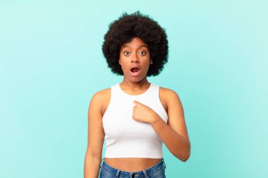 Afro siyah kadın şok olmuş ve şaşırmış görünüyor ağzı açık, kendini işaret ediyor.