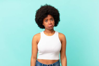 Afro siyah kadın üzgün ve mızmız, mutsuz bir bakışla ağlıyor, olumsuz ve hayal kırıklığına uğramış bir tavırla.