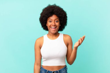 Afro siyah kadın kendini mutlu, şaşırmış ve neşeli hissediyor, olumlu bir tavırla gülümsüyor, bir çözüm ya da fikri fark ediyor.