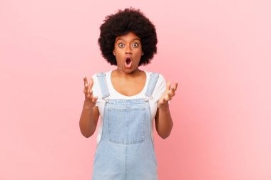 Afro siyahi kadın ağzı açık ve şaşırmış, şok olmuş ve hayrete düşmüş inanılmaz bir sürprizle