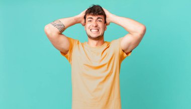 Yakışıklı bir adam stresli, endişeli, endişeli ya da korkmuş, elleri başının üstünde, hata yaptığında panikliyor.