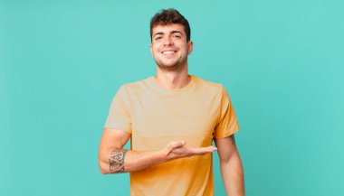 Yakışıklı bir adam neşeyle gülümsüyor, mutlu hissediyor ve fotokopi uzayda avucunun içinde bir konsept gösteriyor.