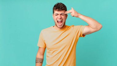 Yakışıklı adam mutsuz ve stresli görünüyor, intihar jesti elle silah işareti yapıyor, kafasını işaret ediyor.