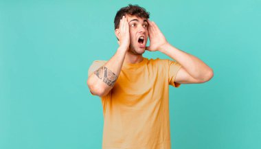 Yakışıklı adam mutlu, heyecanlı ve şaşırmış hissediyor, iki eli yüzü yana bakıyor.