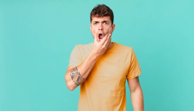 Ağzı ve gözleri açık, eli çenesinde olan yakışıklı bir adam, nahoş bir şekilde şokta, ne ya da vay canına diyor.