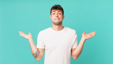 Yakışıklı adam şaşkın ve şaşkın, şüpheci, farklı seçenekleri tartıyor ya da komik bir ifadeyle seçiyor.