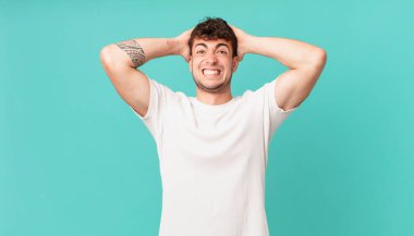 Yakışıklı bir adam stresli, endişeli, endişeli ya da korkmuş, elleri başının üstünde, hata yaptığında panikliyor.