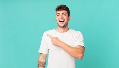 Yakışıklı adam heyecanlı ve şaşırmış görünüyor. Yana ve yukarı doğru uzayı gösteriyor.