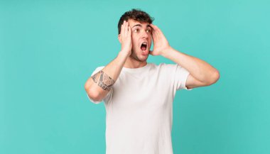 Yakışıklı adam mutlu, heyecanlı ve şaşırmış hissediyor, iki eli yüzü yana bakıyor.