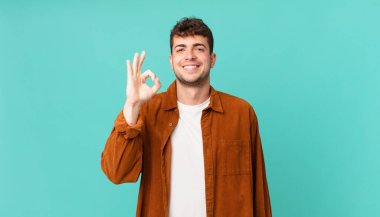 Yakışıklı adam kendini mutlu, rahat ve tatmin olmuş hissediyor. Onayını iyi bir hareketle gösteriyor. Gülümsüyor.