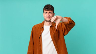 Yakışıklı bir adam kızgın, sinirli, hayal kırıklığına uğramış ya da canı sıkkın, ciddi bir bakışla başparmağını kaldırıyor.