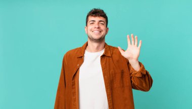 Yakışıklı adam mutlu ve neşeyle gülümsüyor, el sallıyor, seni selamlıyor ya da hoşça kal diyor.