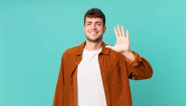 Yakışıklı adam gülümsüyor ve arkadaş canlısı görünüyor, 5 ya da 5 numarayı gösteriyor, eli önde, geri sayıyor.