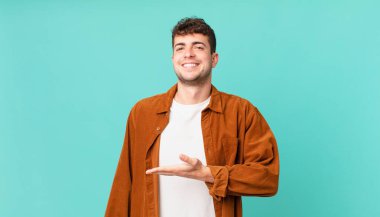 Yakışıklı bir adam neşeyle gülümsüyor, mutlu hissediyor ve fotokopi uzayda avucunun içinde bir konsept gösteriyor.