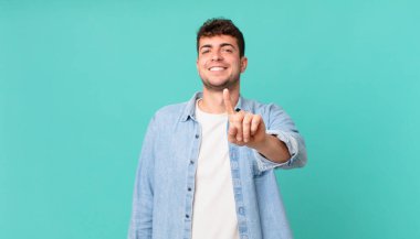 Yakışıklı adam gururla gülümsüyor ve gururla bir numaralı pozunu veriyor, kendini lider gibi hissediyor.