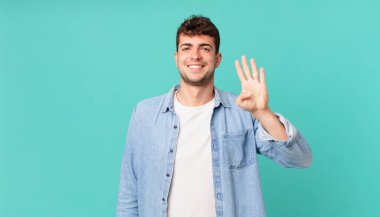 Yakışıklı adam gülümsüyor ve arkadaş canlısı görünüyor. Elleri önde, geriye doğru sayıyor.