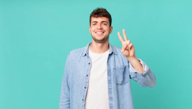 Yakışıklı adam gülümsüyor ve arkadaş canlısı görünüyor. İki ya da iki numarayı gösteriyor. Elleri önde, geriye doğru sayıyor.