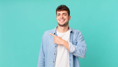 Yakışıklı adam heyecanlı ve şaşırmış görünüyor. Yana ve yukarı doğru uzayı gösteriyor.