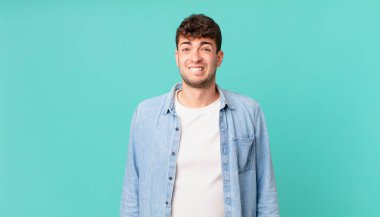 Yakışıklı adam şaşkın ve şaşkın görünüyor, gergin bir hareketle dudağını ısırıyor, sorunun cevabını bilmiyor.