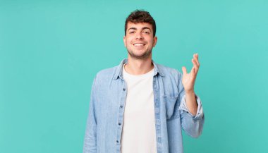 Yakışıklı adam kendini mutlu, şaşırmış ve neşeli hissediyor. Pozitif bir tavırla gülümsüyor. Bir çözüm ya da fikir buluyor.