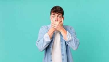 Yakışıklı bir adam elleri ile ağzını kapatıyor, şok olmuş, şaşırmış bir ifadeyle, sır saklıyor ya da 