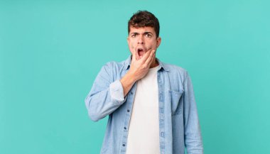 Ağzı ve gözleri açık, eli çenesinde olan yakışıklı bir adam, nahoş bir şekilde şokta, ne ya da vay canına diyor.