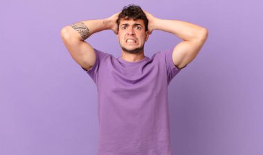 Yakışıklı bir adam stresli, endişeli, endişeli ya da korkmuş, elleri başının üstünde, hata yaptığında panikliyor.