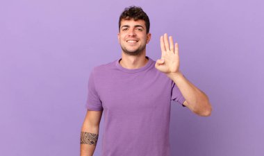 Yakışıklı adam gülümsüyor ve arkadaş canlısı görünüyor. Elleri önde, geriye doğru sayıyor.