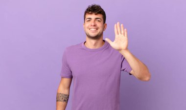 Yakışıklı adam gülümsüyor ve arkadaş canlısı görünüyor, 5 ya da 5 numarayı gösteriyor, eli önde, geri sayıyor.