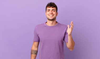 Yakışıklı adam kendini mutlu, şaşırmış ve neşeli hissediyor. Pozitif bir tavırla gülümsüyor. Bir çözüm ya da fikir buluyor.