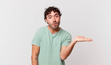 İspanyol yakışıklı adam şaşırmış ve şoka uğramış görünüyor, çenesi düşmüş, bir objeyi elinde açık bir elle tutuyor.