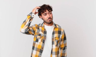 İspanyol yakışıklı adam şaşkın ve şaşkın hissediyor, başını kaşıyor ve yana bakıyor.