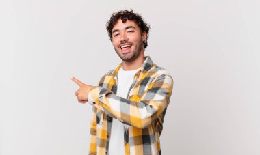 İspanyol yakışıklı adam heyecanlı ve şaşırmış görünüyor. Yana ve yukarı doğru uzayı gösteriyor.