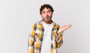 İspanyol yakışıklı adam şaşırmış ve şoka uğramış görünüyor, çenesi düşmüş, bir objeyi elinde açık bir elle tutuyor.